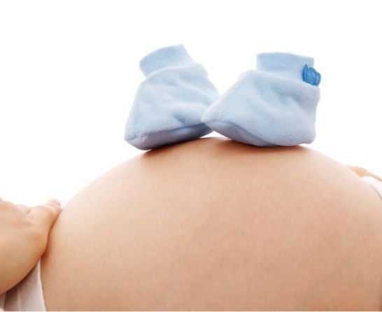 blue baby shoes on pregnant belly