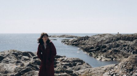 women in coat next to the ocean